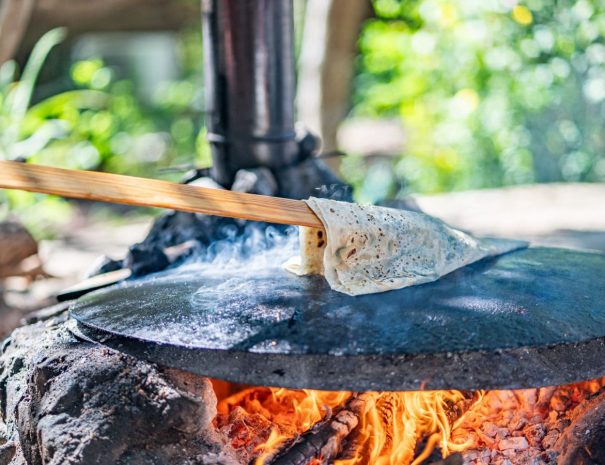 Frisch gebackenes Gözleme-Fladenbrot auf einer heißen Eisenplatte über dem offenen Feuer – traditionelle türkische Zubereitung in der Natur.